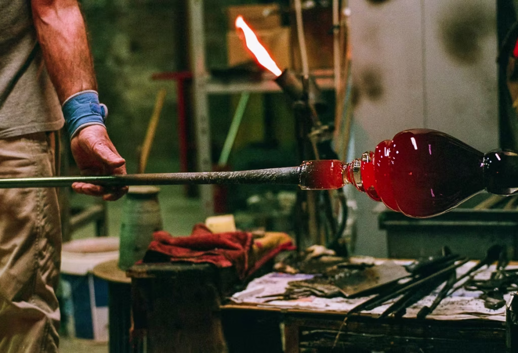 Murano glass artisan shaping molten glass in a Venetian workshop