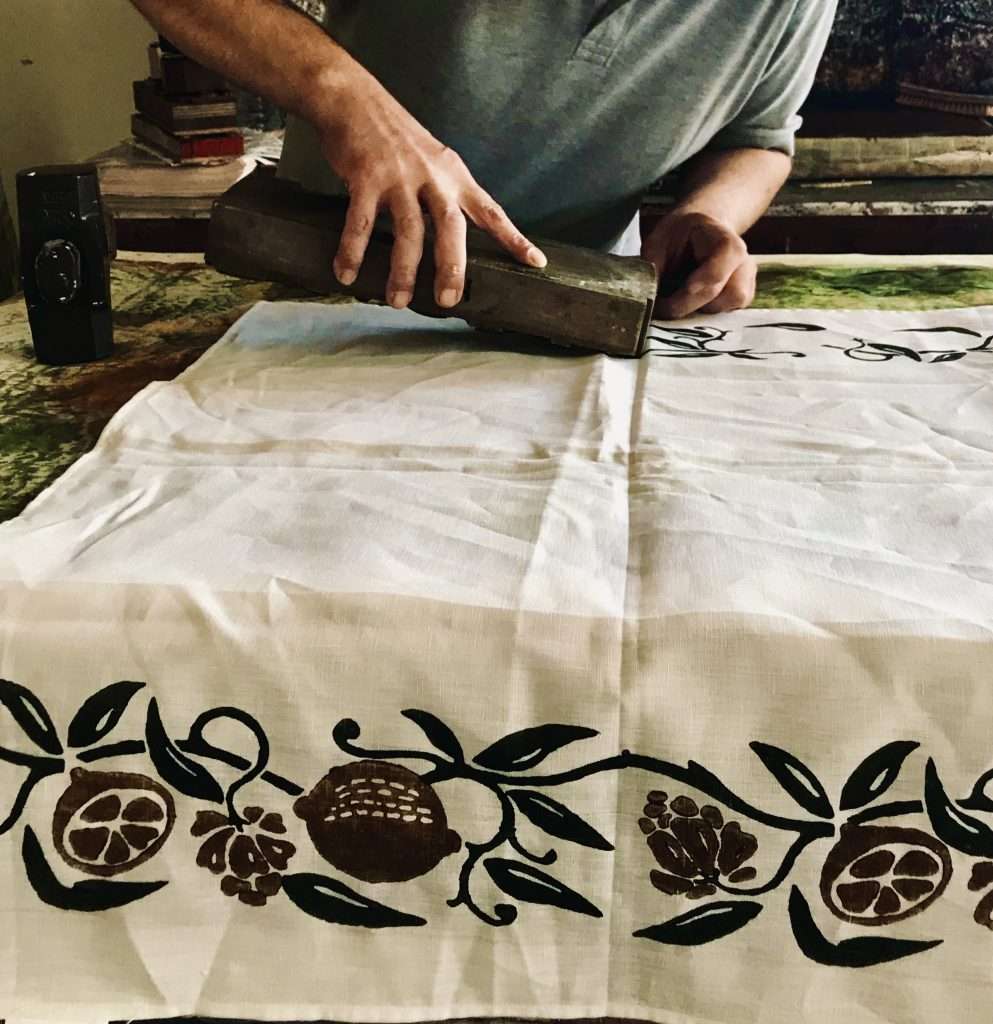 Italian artisan block printing a linen tea towel in lemon pattern