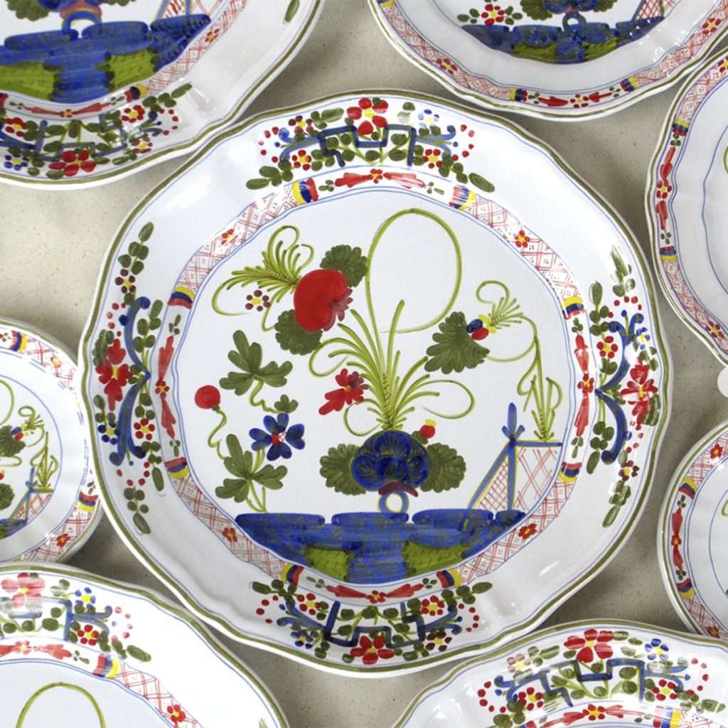Close-up of a hand-painted majolica ceramic plate showing subtle variations in glaze thickness from manual brushwork and a dense, smooth glass-like layer over a clay base.