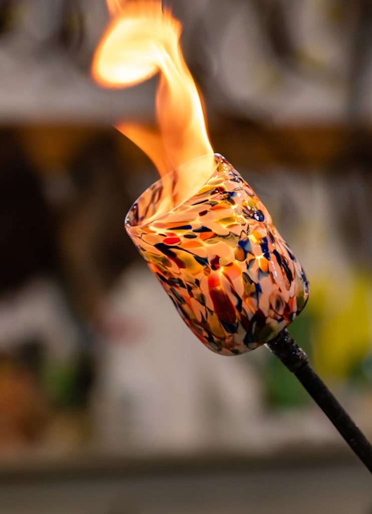 Flames dance amidst glowing glass in a Murano, Italy glassblowing workshop, creating mesmerizing patterns and shapes.
