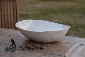 Luxury Italian bowl handmade of Limoges porcelain laid on a wooden table in the outside