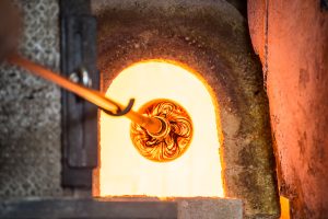 Artisan introducing a lump of Murano glass into the furnace